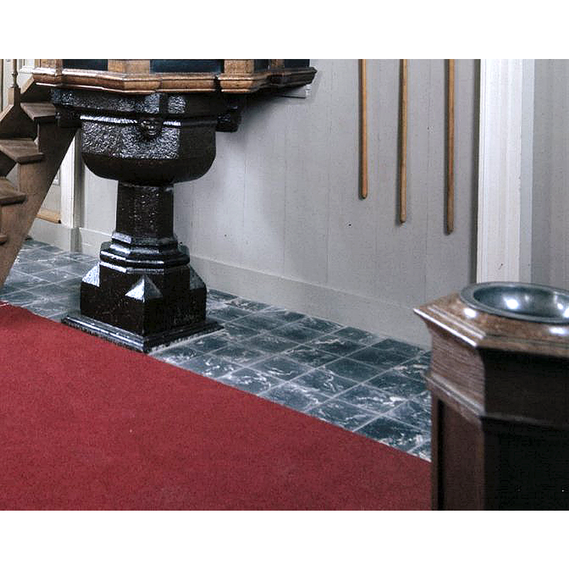 The image shows two fonts: on the left is the heavily painted old font still supporting the pulpit; in the bottom-left corner the later wooden font may be partially seen.
