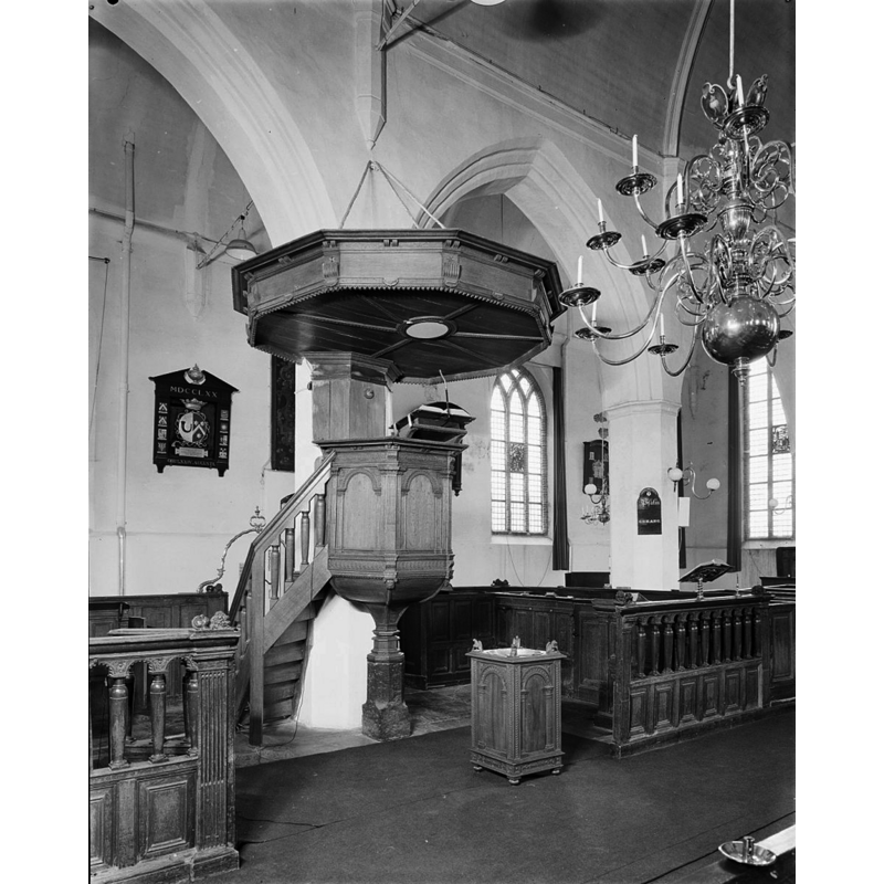 Source caption: "Nederlands Hervormde Kerk: preekstoel en doopvont" -- the stone support of the 1610 wooden pulpit may be the former base of a baptismal font [cf. FontNotes]; the wooden quadrangular object on the ground in front of the pulpit is probably the modern baptismal font