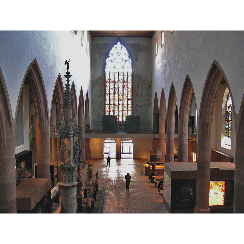 Source caption: "Historisches Museum Basel in der Barfüsserkirche. Blick von der Chorempore in Richtung Eingang, links historische Brunnenstöcke, rechts Museumsshop und Kasse sowie Cafeteria."
