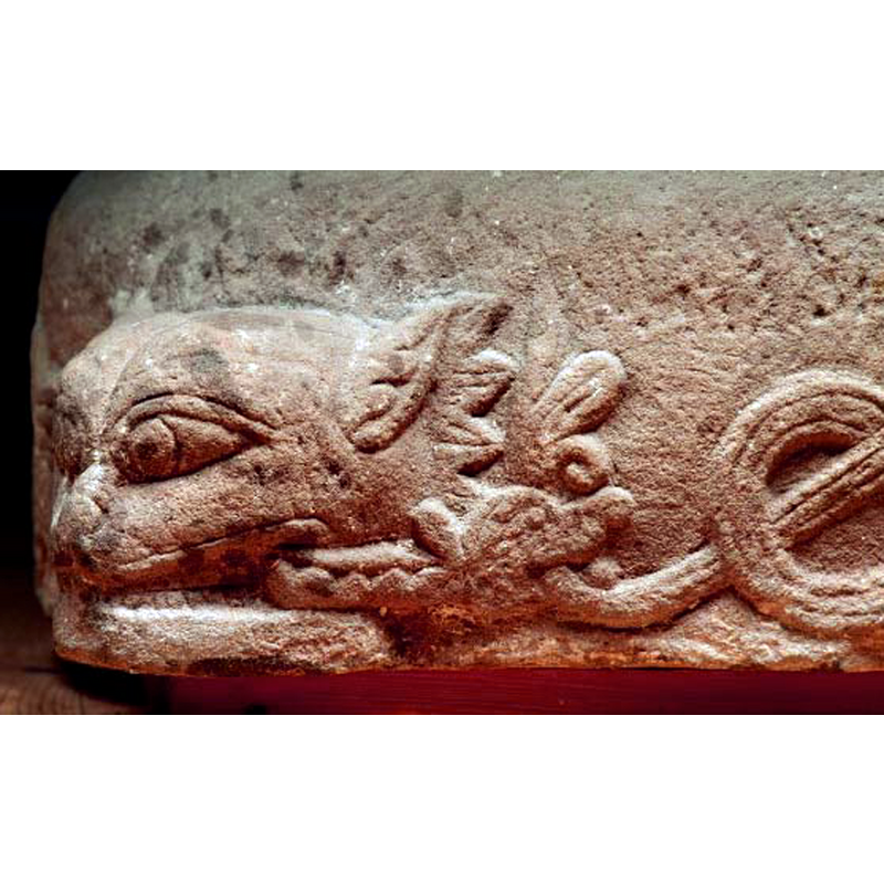 the corner animal head is biting a tiny dragon that, itself, bites the foliated tail of an animal -also a dragon- partially visible on the right