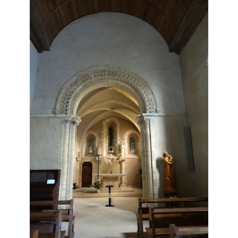Source caption: "Église Notre-Dame de l'Assomption de Colleville-sur-Mer, l'arc triomphal en plein-cintre dont l'archivolte est décorée de motifs géométriques typiques de l'époque romane en Normandie, sépare la nef du chœur."