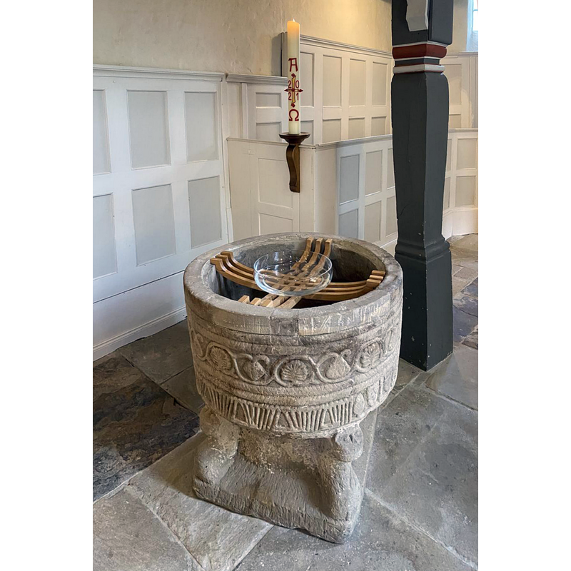 the medieval font is seen here with a simple glass baptismal dish