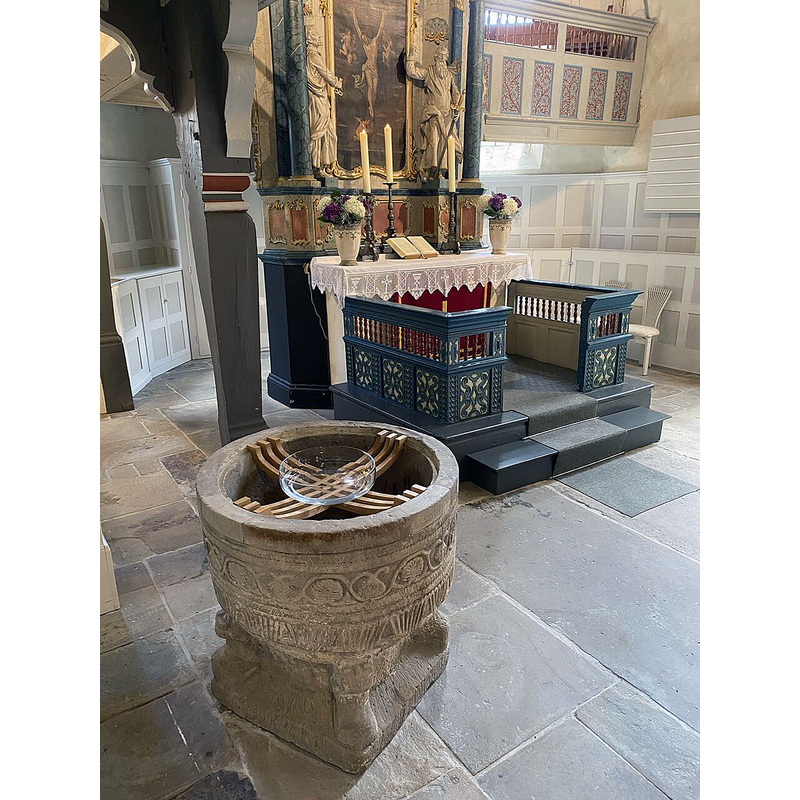 the medieval font is seen here with a simple glass baptismal dish