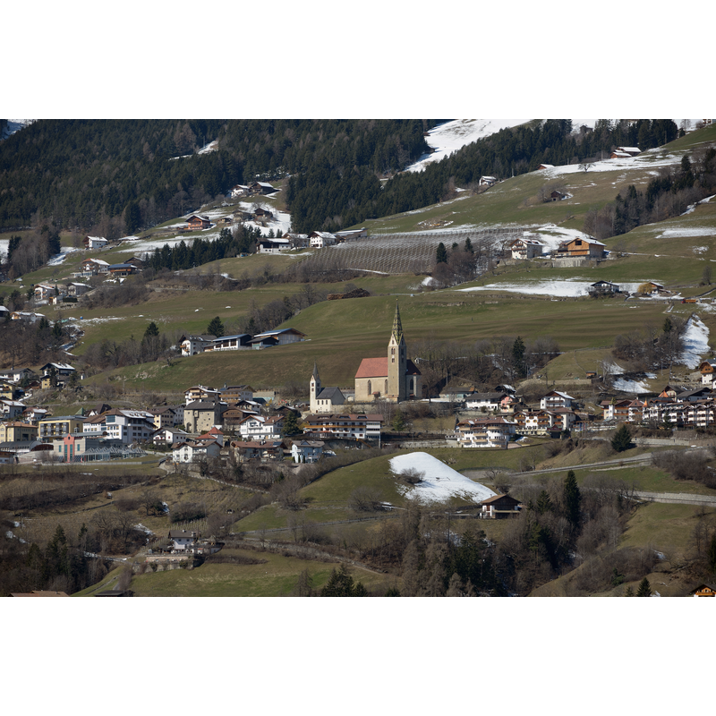 Source caption: "Villandersin Südtirol und in der Bildmitte die Pfarrkirche St. Stephan - Spitzturm um 1400, Kirche zu Beginn des 16. Jh.s neu gebaut und 1521 vollendet. Polygonaler Chorschluß, Netzrippengewölbe. Empore, 17. Jh. Historistische Dekorationsmalerei; außen Wandgemälde (Christophorus), bez. 1569. St. Michael am Friedhof: Zweigeschossiger Bau mit Spitzbogentüren, 1344 geweiht. Spitzturm, Untergeschoß mit Beinhaus und flachgedeckter Kapelle mit Spitzbogentür. Obere Kapelle mit Flachdecke, im Osten Ansatzstelle der ursprünglichen Apsis. Spitzbogentür, Rechteckfenster"