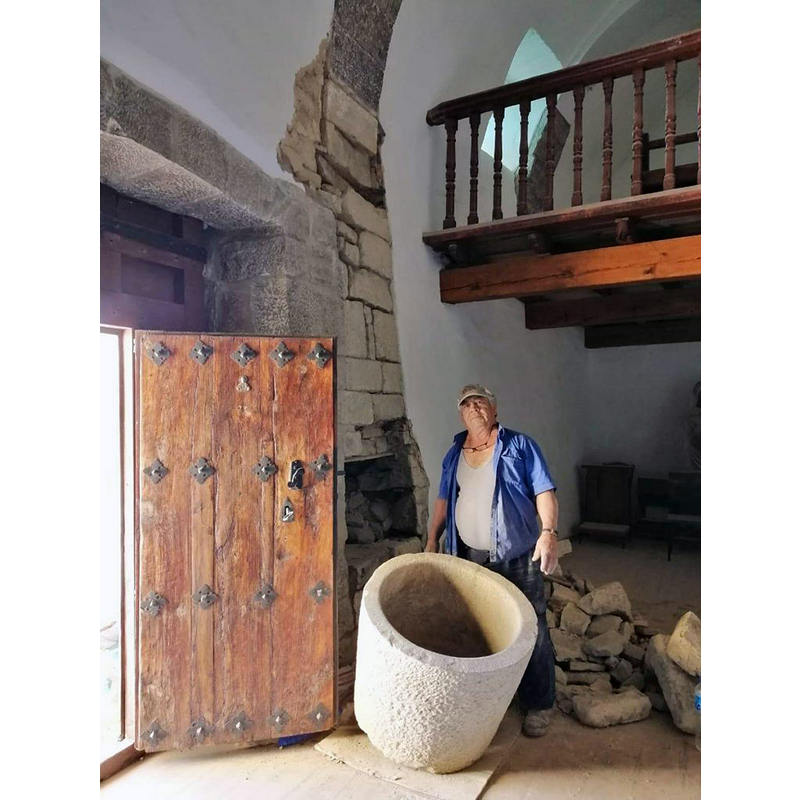 the hole in the wall behind the door is where the font had been walled; the man behind the font is Miguel Angel Bezunartea, the local volunteer who was working in the restoration of the church when the font was discovered