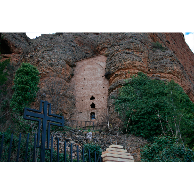 Source caption: "Ermita de San Benito, construida en una grieta natural, entre paredes de arenisca." -- a nearby rural chapel built onto the rock face