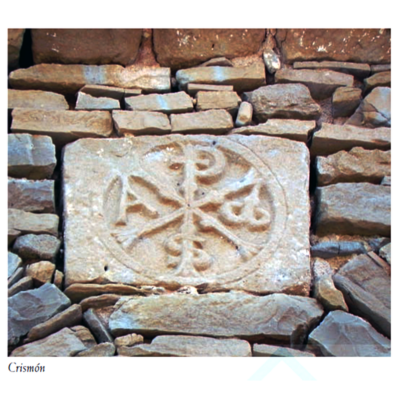 Source caption: "El crismón románico se encuentra en el cuerpo de campanas de la torre, en su muro oeste. Se trata de un crismón de tipo trinitario, con influencias navarras"