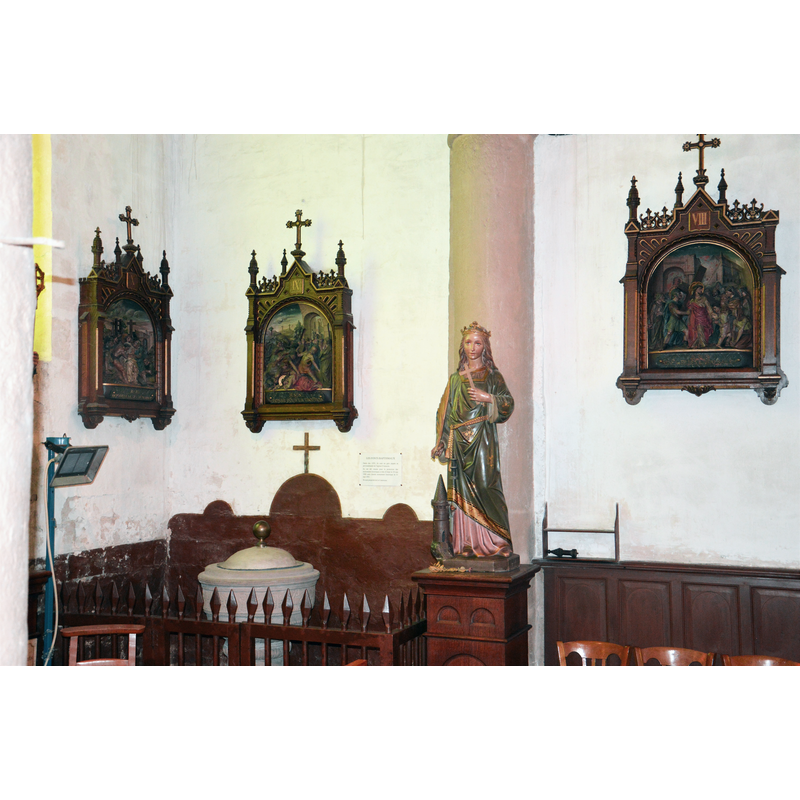 Source caption: "Houchin, église St Omer, fond de l'église (côté de l'autel de St Joseph). Zone des fonts baptismaux, statue de Sainte Barbe, chemin de croix en terre cuite."