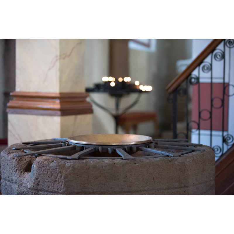 notice the damage; likely caused by an anchoring from an old font -- the metal rack holds the baptismal dish in place for baptisms