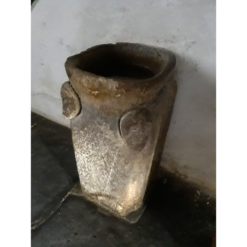 an object described in the Enciclopedia as an object that appears to be used as a holy-water stoup: "adosada al muro septentrional, se encuentra una pieza que ha sido mal interpretada como pila bautismal. Se trata de un bloque monolítico que ronda el metro de altura, de cuerpo prismático cuadrangular y remate superior en forma de copa, en el que han tallado dos pequeñas cabezas humanas de forma elemental y primitiva. Este elemento debe de proceder de la fábrica primitiva, pero fue sometido a una intervención para cumplir la función de benditera."