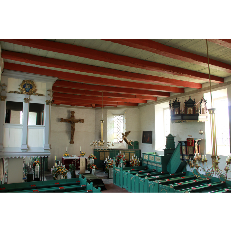 Source caption: "Innenraum der Kirchbarkauer Kirche " -- notice that, although the baptismal angel hangs near the southeast window, in the right side of the image, the baptismal font is partially visible in the bottom-left corner of the image, semi-vuried in flowers and candles