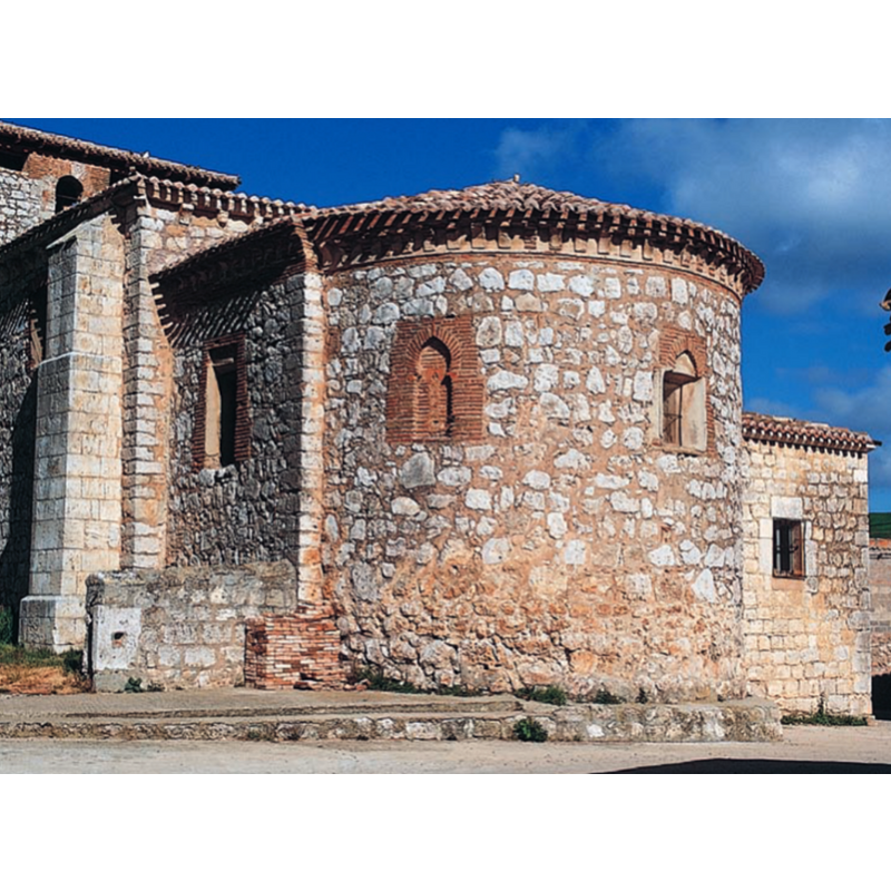 Source caption: "En el tambor absidal se abren tres ventanas formadas por una estrecha aspillera cobijada por un arco tumido, mientras que en el lado sur del presbiterio se abría otra enmarcada por un friso de esquinillas, transformada posteriormente al igual que una del ábside. Se remata la cabecera con una cornisa de ladrillo –originalmente enfoscada– decorada con una serie de canecillos del mismo material."