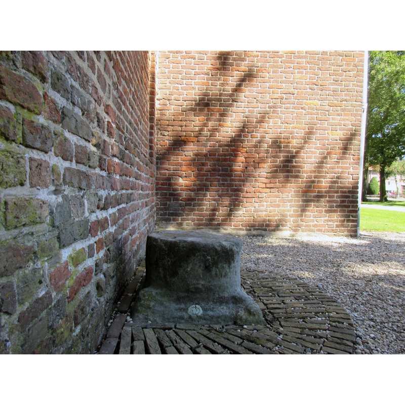the base of the medieval font here, according to one source [cf. FontNotes]: Outside the church is the base and column of the font, and these were used as "roepsteen" or "pierre de criée" for public announcements.