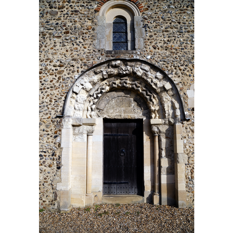 Source caption: "The lead-flashed hood-moulded Romanesque tower west portal and door of the Grade I listed Holy Cross Church on the B1417 Braintree Road, Felsted, Essex, England."