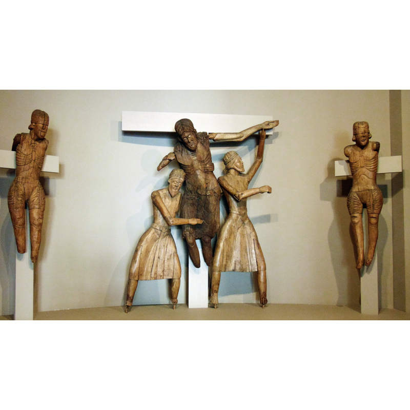 Source caption: "Museu episcopal de Vic. 9-8-2019. Taller d'Erill, primera meitat del s. XII. Fusta d'alba i noguera amb restes de policromia al tremp. Provinent de l'església de Santa Eulàlia d'Erill la Vall. La Vall de Boí (Alta Ribagorça). Aquest grup escultòric representa el moment en que Josep d'Arimatea i Nicodem baixen el Crist mort de la Creu. Al costat hi ha les figures dels dos lladres Dimes i Gestes. Les figures de Maria i Sant Joan es conserven al Museu Nacional d'Art de Catalunya."