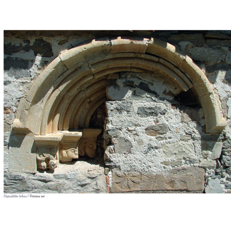 Source caption: "En el muro sur del presbiterio se encuentra, aunque incompleto, un hermoso ventanal románico que ha quedado al descubierto al derrumbarse la sacristía que se encontraba adosada a este lado del templo. Consta de arco de medio punto, tres arquivoltas de bocel y guardapolvo con perfil de nacela. En el lado izquierdo han quedado a la vista tres capiteles decorados con una cabeza masculina, otra femenina con tocado de barbuquejo y un monstruo fantástico acompañado de serpientes."