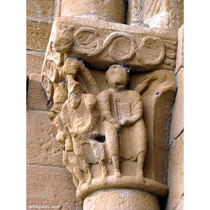 Source caption: "El segundo capitel muestra a tres personas frontales con objetos en sus manos, pero sólo de uno estamos seguros: báculo y libro." [NB: the identitification of the third person by the baculum and the book is probably in reference to the original nature of this church, which, as the same author notes, "La que hoy es considerada ermita del Santo Cristo de Cataláin, fue una importante iglesia de un monasterio particular fundado en el siglo XII en el extremo occidental de la famosa comarca de la Valdorba (Valle de Orba), una de las zonas de la Comunidad de Navarra con mayor densidad de monumentos y restos románicos."]