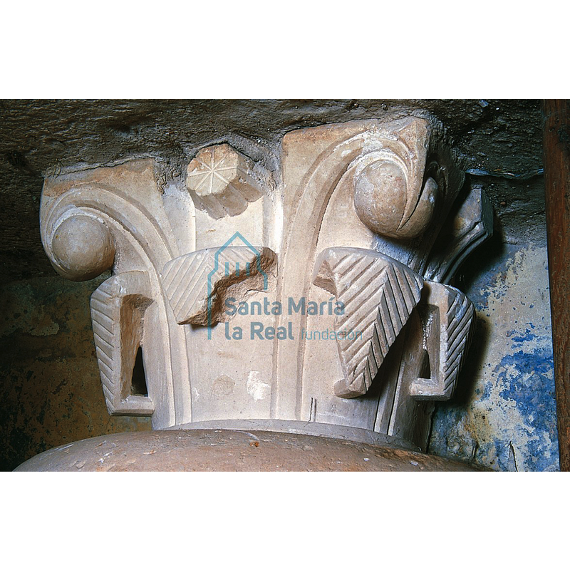 Source caption: "un capitel vegetal hoy utilizado como peana de la moderna pila bautismal de la iglesia de Mambrillas de Lara (en este templo se conserva una fragmentada pila gallonada cuya talla a trinchante revela su gótica cronología). Se decora con dos pisos de hojas, las inferiores de puntas dobladas y nervadas y las superiores lisas y rematadas por bolas con caperuza." [NB: shown here vertically flipped from its actual position suporting the basin of the Mambrillas font]