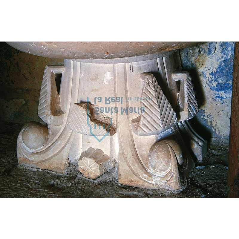 Source caption: "un capitel vegetal hoy utilizado como peana de la moderna pila bautismal de la iglesia de Mambrillas de Lara (en este templo se conserva una fragmentada pila gallonada cuya talla a trinchante revela su gótica cronología). Se decora con dos pisos de hojas, las inferiores de puntas dobladas y nervadas y las superiores lisas y rematadas por bolas con caperuza." [NB: shown here in its actual position suporting the basin of the Mambrillas font]