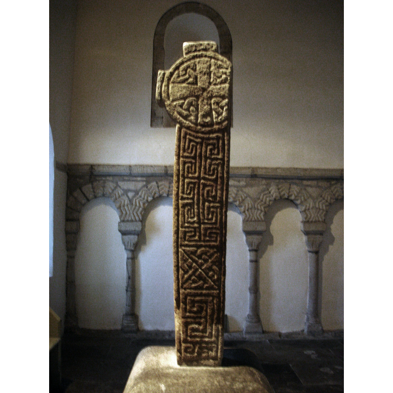 Source caption: " 10th century cross from St Seiriol's Church, Penmon, Anglesey. One arm was removed for use as a lintel. The stone base records the moving of the stone by the Cambrian Archeological Society in 1895."