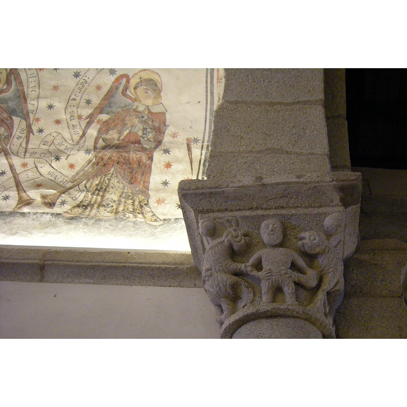 Source caption: "Capitel situado en el lado izquierdo del arco triunfal en el que se muestra una figura humana rodeada por dos bestias."