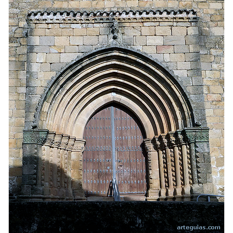 Source caption: "Pero lo que le ha aportado notoriedad al templo es, sobre todo, su puerta meridional pues se suele considerar tardorrománica del siglo XIII. Pero incluso si fuese de una época tan avanzada como el siglo XV sería evidente una gran arcaización de la estructura arquitectónica y de la escultura que nos llevaría a pensar en una inspiración (o incluso imitación) de modelos más antiguos, como la puerta occidental de la Catedral Vieja de Plasencia."