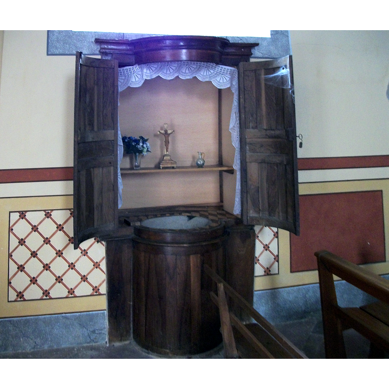Source caption: "Église Saint-Saturnin [...] Le baptistère" -- the baptismal font of stone 'wrapped' in a wooden armoire