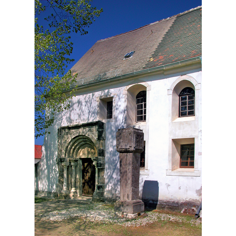 Source caption: "Dorfkirche Hayna (GMP: 51.430650,12.310580). Ursprünglich romanisches Gotteshaus aus Feld- und Bruchsteinen. Auch das aufwändige Sandsteinportal auf der Südseite stammt aus der Romanik und erinnert an die Schmuckformen der Doppelkapelle von Landsberg und der Kirche von Naundorf bei Halle. Es stammte wohl mal von einer anderen, bedeutenderen Kirche, aber niemand weiß, von wo. Im 15. Jahrhundert wurde der spätgotischer Chor angefügt. Fast wäre die Kirche nach dem unerwarteten Einsturz des Kirchturmes im Jahre 1972 völlig abgerissen worden. Doch der Gemeindekirchenrat verweigerte damals die letzte Zustimmung und machte sich an den Wiederaufbau der Kirche. Südseite."