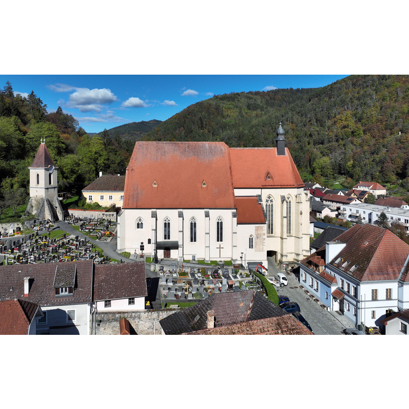 Source caption: "Südansicht der Pfarrkirche hl. Stephanus und links der freistehenden Glockenturm in der niederösterreichischen Marktgemeinde Weiten.
Erbaut wurde die gotische Pfarrkirche in der Zeit von 1330 bis 1360 und 1473 erfolgte die Erweiterung zur Wehrkirche. Etwas Besonderes sind der gotische Chor sowie die berühmten Maßwerkfenster mit Glasmalereien aus dem 14. und 15. Jahrhundert und der abseits stehende Glockenturm"