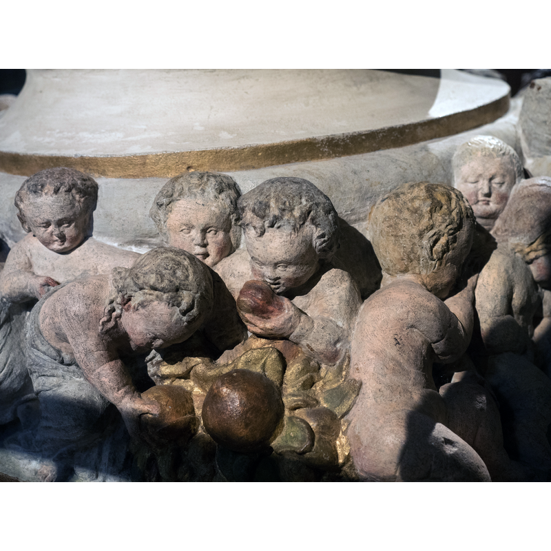 Source caption: " Fuß des Taufsteines der Marienkirche zu Pirna von 1561, Christoph Kramer aus Dresden zugeschrieben" -- children, some dressed, some naked; they hug, eat, drink, look at each other, play with animals, sleep, etc.