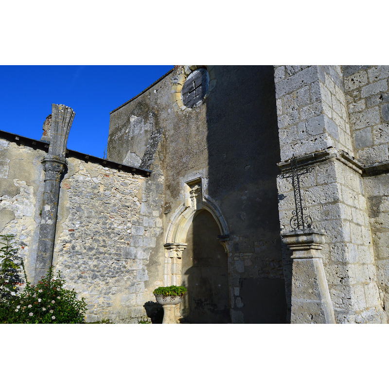Source caption: "Façade principale de l'ancienne église Saint-Pierre-aux-Liens. Au-dessus du porche, on distingue une niche dans laquelle est sculptée une coquille, témoin de la situation de l'édifice sur la route de Saint-Jacques-de-Compostelle." -- notice the 18thC font or stoup used as planter by the portal