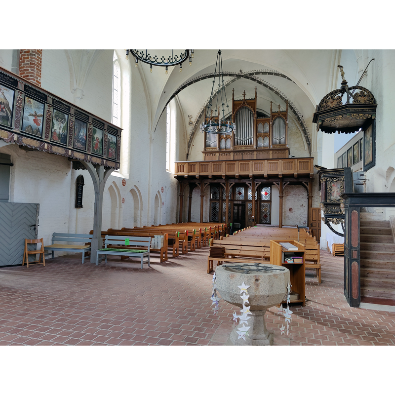 Source caption: " Innenraum mit Mehmel-Orgel (1863, restauriert 1993) der Evangelischen Dorfkirche Steinhagen, Landkreis Vorpommern-Rügen, Mecklenburg-Vorpommern, Deutschland" -- showing the medieval font in the foreground