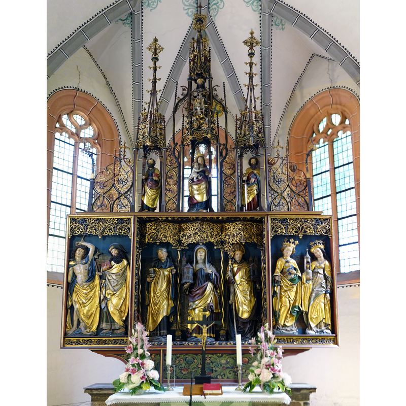 Source caption: "Gertrudiskirche (Saalfeld-Graba), 7 m hoher spätgotischer Schnitzaltar aus Saalfelder Schule. Die Figuren wurden etwa 1510 von Hans Gottwald von Lohr angefertigt. Im Mittelteil befinden sich die lebensgroßen Figuren der heiligen Gertrud zwischen Benedikt von Nursia und Anno von Köln. In den geöffneten Flügeln stehen die in Flachreliefs ausgeführten Heiligen Sebastian und Jakobus der Ältere sowie Katharina und Barbara. Der filigran geschnitzte Auszug über dem Schrein wird geschmückt von den Figuren der Maria mit Kind zwischen Petrus und Paulus; im obersten Teil erscheint die Figurengruppe des Gnadenstuhls oder der Heiligen Dreifaltigkeit."