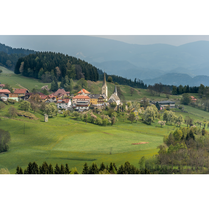 Source caption: "West-Ansicht des Wehrdorfes Sörg mit der Pfarrkirche hl. Martin, Marktgemeinde Liebenfels, Bezirk Sankt Veit, Kärnten, Österreich, EU" -- two church towers visible here: on the left is the Romanesque "Chorturm"; on the right the tower of the late-Gothic church