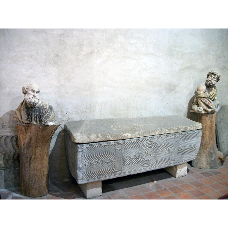 Source caption: "Sarcophage paléochrétien orné de chevrons opposés, coupés par des pilastres cannelés et rudentés, au centre un chrisme inversé, il est entouré de deux bustes."
