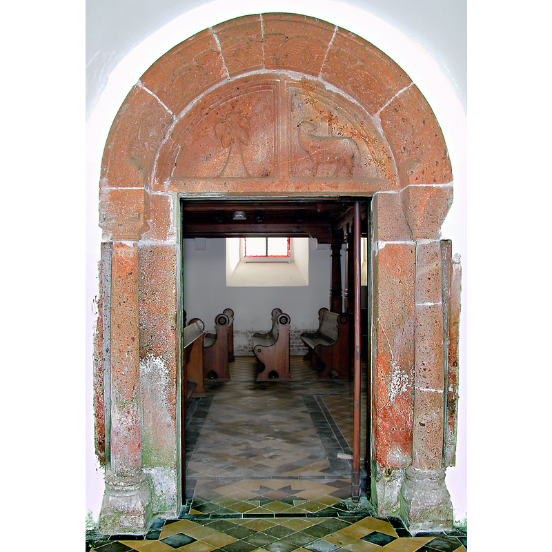 Source caption: " Knobelsdorf (Waldheim; bis 2012 Ziegra-Knobelsdorf): Dorfkirche [...] Im Kern romanische Saalkirche, in gotischer Zeit erneuert, 1893 nach Plänen des Architekten Theodor Quentin stark verändert. Romanisches Nordportal (Ende 12. Jahrhundert). Aus rötlichem Rochlitzer Porphyr gehauen, zeigt es im Bogenfeld links eine Palme. Rechts erscheint ein Lamm mit Kreuz."