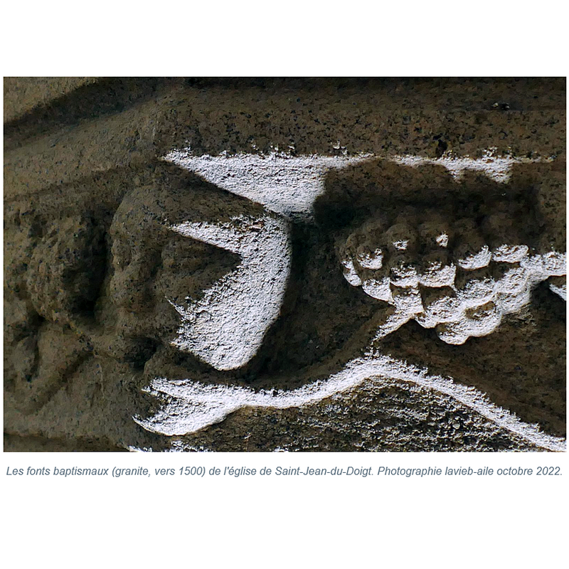 somewhat similar to the head on its left byt this one has two grapevines issuing from its mouth, running in opposite directions, left and right