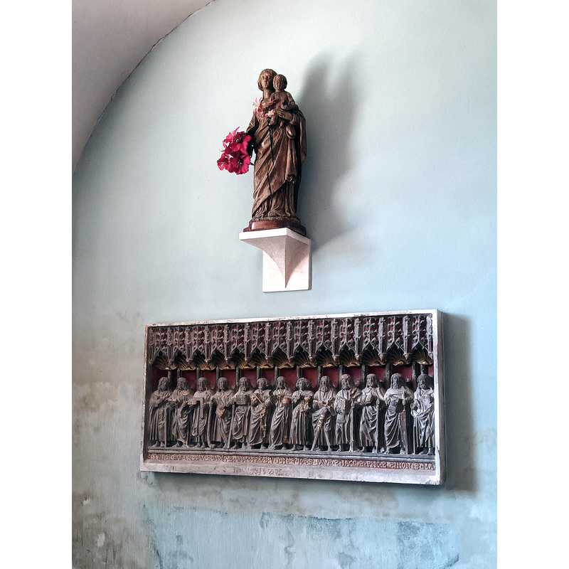 Source caption: "Le retable « Le Christ et les Apôtres » et la Vierge à l'Enfant en bois visibles dans la chapelle des Fonts baptismaux." -- showing the famous 1528 retable in the background and the Madonna statu inside the chapelle baptismale