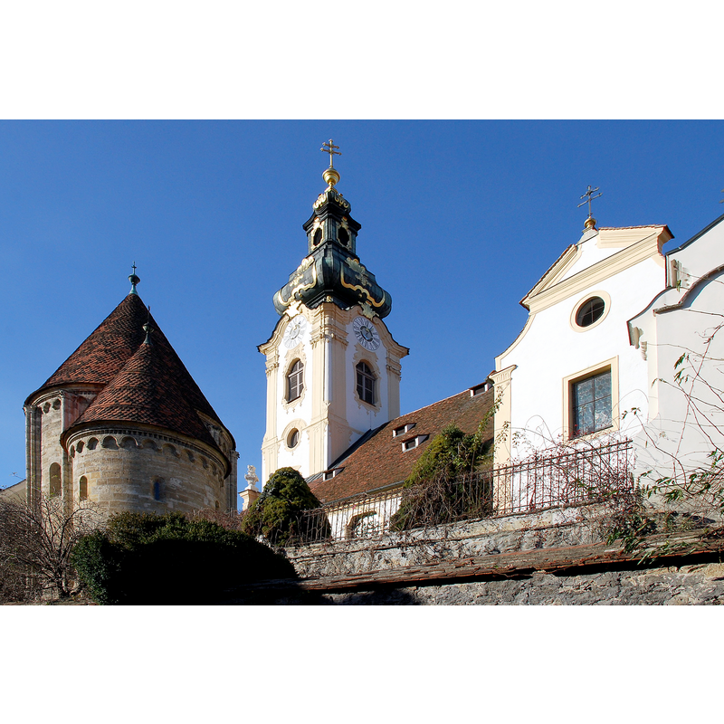 Source caption: "Hartberg, Steiermark, Österreich: Pfarrkirche und Karner" -- showing the Baroque church with the Romanesque-style ossuary on the left