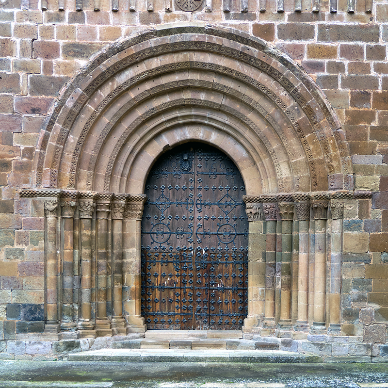 Source caption: "Portada occidental de la iglesia abacial, su abocinamiento y características apuntan a un románico final (finales del siglo XII)."