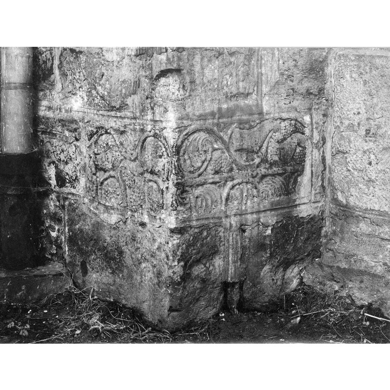 the fragments of the old font wall-mounted on the apse wall
