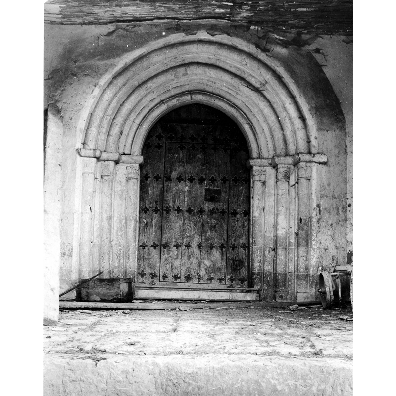 Source caption: "Portada de la iglesia de San Andrés. Detalle de la portada. Presenta un arco ligeramente apuntado, con arquivoltas sin decorar y capiteles levemente ornamentados con hojas estilizadas"