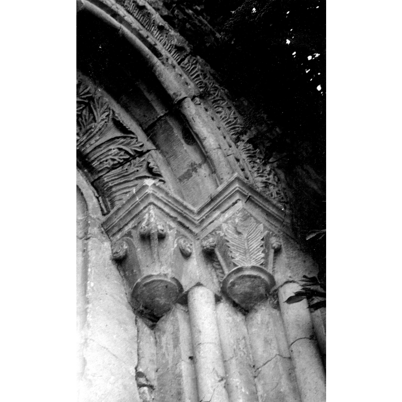 Source caption: "Parte superior derecha de una ventana de la ermita de Nuestra Señora de Urrialdo de Mártioda en Álava. Vista frontal de una parte de la ventana. Destaca la decoración de la arquivolta con hojas de acanto, lo mismo que el trasdós. El arco se apea en dos columnas de las que sólo se conservan los capiteles con decoración vegetal"
