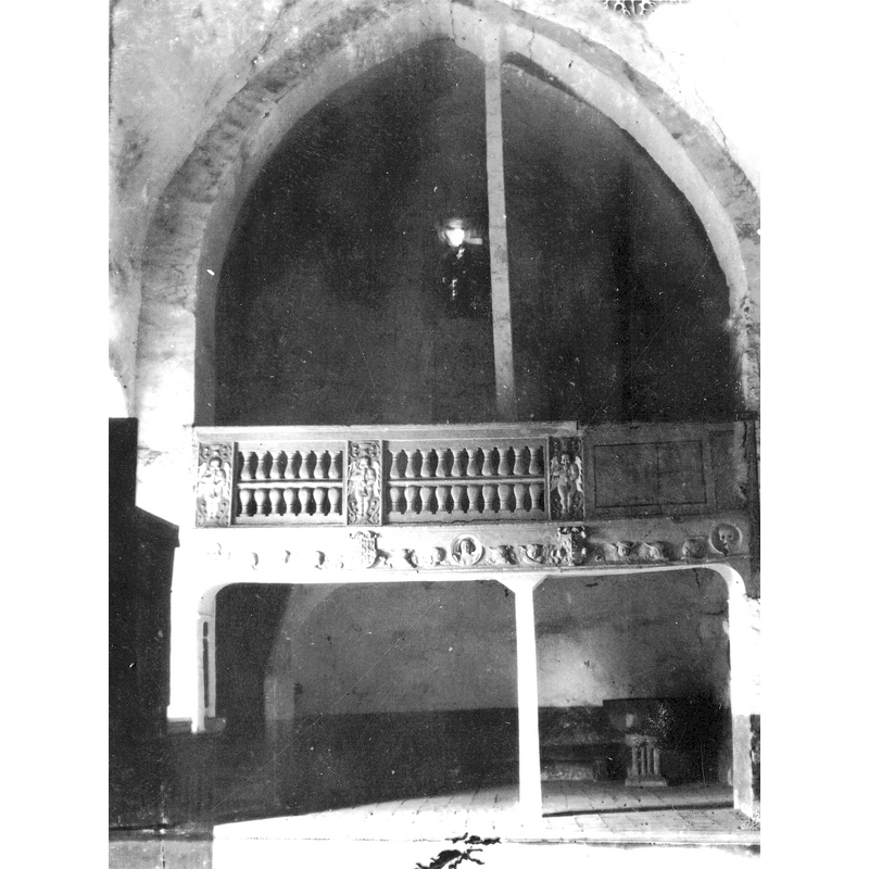 Source caption: "Coro de la ermita de Nuestra Señora de Urrialdo de Mártioda en Álava. Vista del interior de la ermita. Destaca el coro de estilo renacentista con una balaustrada de piedra entre cuatro pilastras con ángeles desnudos muy frontales y con manos juntas entre grutescos. El dintel se decora con cabezas de ángeles, calaveras, los escudos de los Mendoza de Mártioda y otro escudo" -- the baptismal font is visible in the lower-left corner of the ima -- was this photograph taken before the 1935 fire that gutted the church?