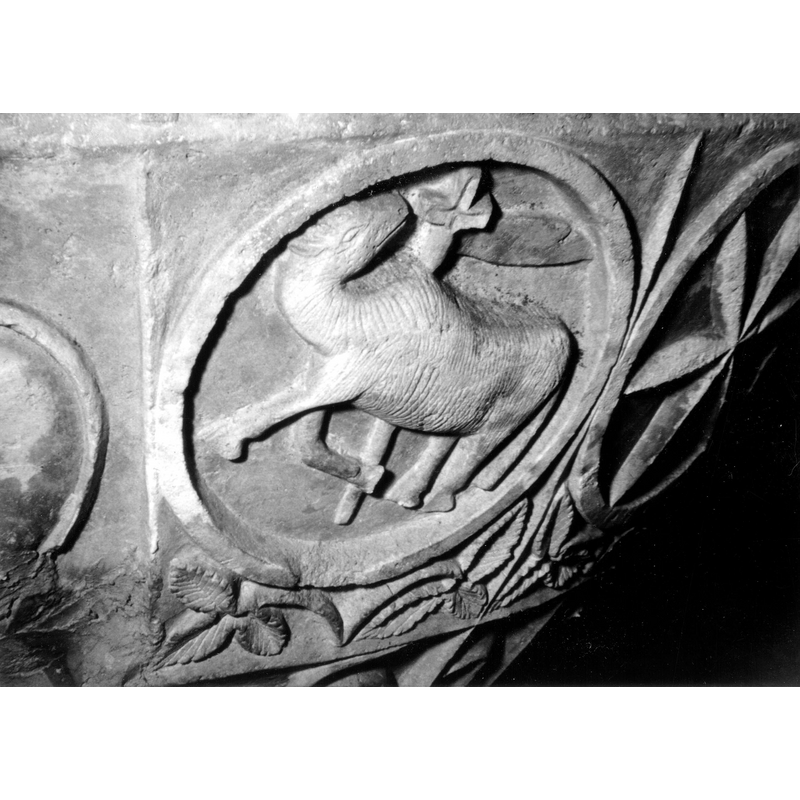 Source caption: "Detalle de la segunda faja de la pila bautismal; se representa al Agnus Dei dentro de un círculo [...] pila bautismal de la iglesia de la Natividad de Hueto Arriba"