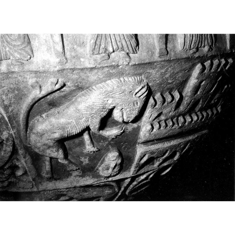 Source caption: "Detalle de la segunda franja de la pila bautismal de estilo gótico; se representa un león rampante con una cabeza abatida en la parte inferior [...] pila bautismal de la iglesia de la Natividad de Hueto Arriba"