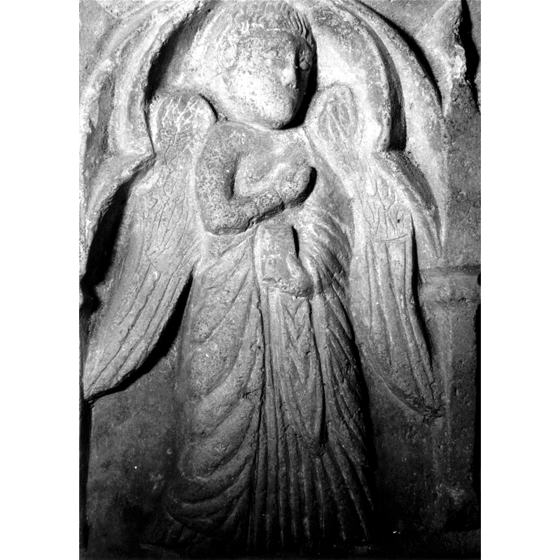 Source caption: "Detalle de una de las figuras de la parte superior de la pila bautismal gótica; se representa la escena de la Anunciación. Es un detalle de la figura del arcángel [...] pila bautismal de la iglesia de la Natividad de Hueto Arriba"