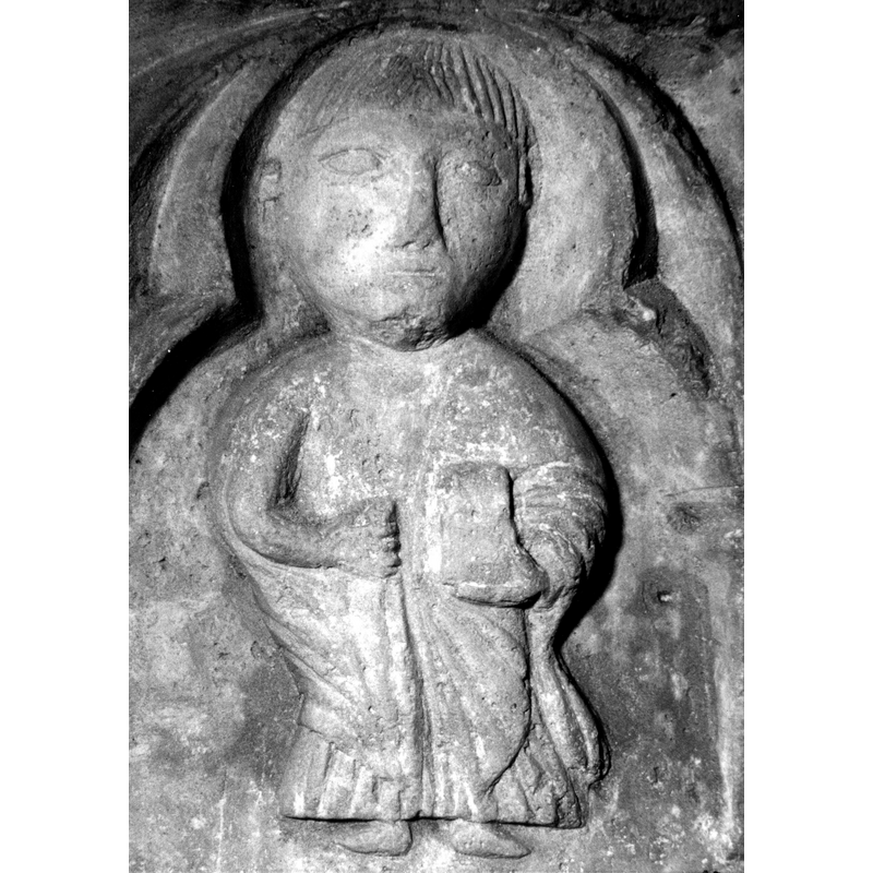 Source caption: "Detalle de una de las figuras de la parte superior de la pila bautismal gótica; se representa una figura de hombre, posiblemente San Pablo con la espada en las manos, entre arquerías polilobuladas [...] pila bautismal de la iglesia de la Natividad de Hueto Arriba"