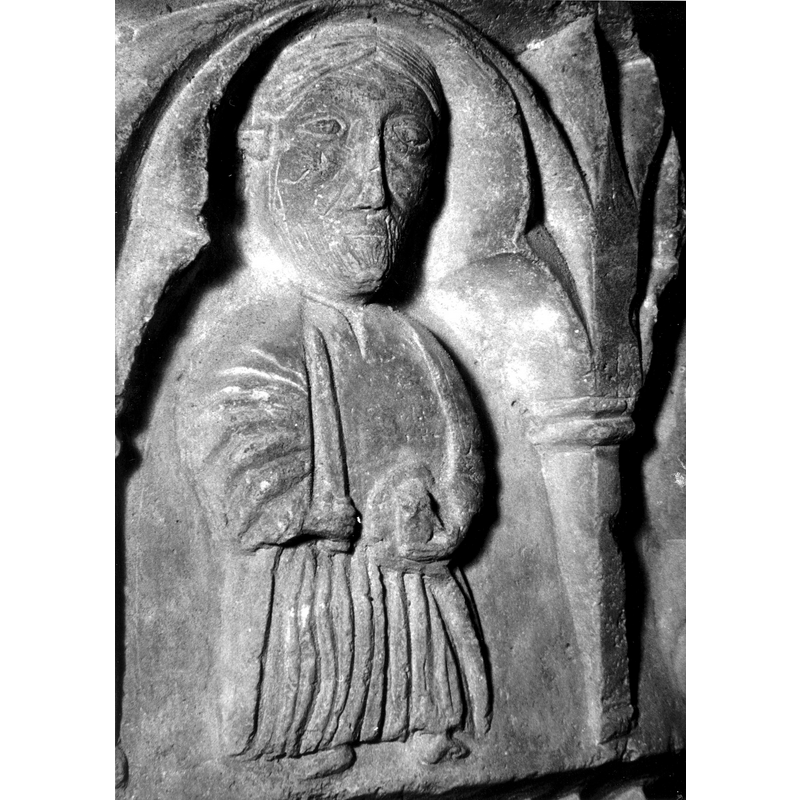 Source caption: "Detalle de una de las figuras de la parte superior de la pila bautismal gótica; se representa una figura de apóstol con una espada en la mano entre arquerías polilobuladas [...] pila bautismal de la iglesia de la Natividad de Hueto Arriba"