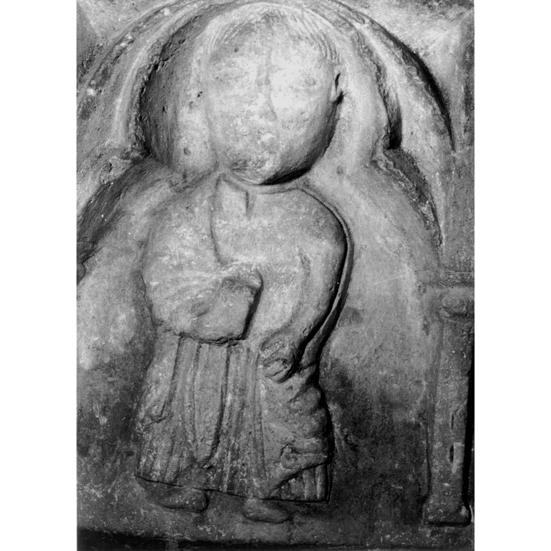 Source caption: "Detalle de la parte superior de la pila bautismal; presenta, entre arquerías polilobuladas, una figura humana que puede representar a un apóstol, un profeta o un fraile franciscano con libros o cartelas en las manos [...] pila bautismal de la iglesia de la Natividad de Hueto Arriba"